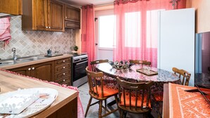 Eine Küche mit Holzausstattung, einem Esstisch mit Stühlen, einem Kühlschrank und einem Fenster mit rosa Vorhängen.