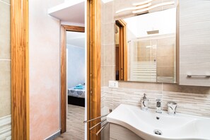 Une salle de bain moderne avec un grand lavabo, un miroir et une porte en bois.