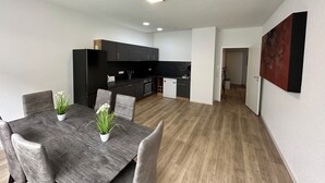 A modern kitchen with dark cabinets and a dining area with a wooden table and chairs. - Big Family Suite with 7 beds in the center of Göppingen (Göppingen)