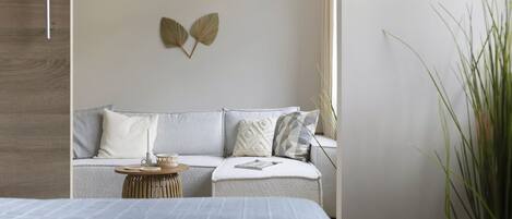 A modern bedroom with a bed, a sofa, and a small side table.