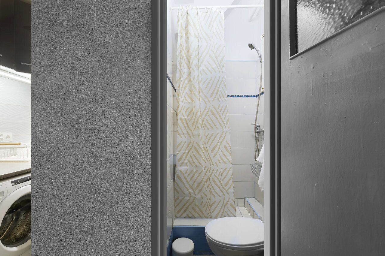 A compact bathroom with a shower, toilet, and washing machine.