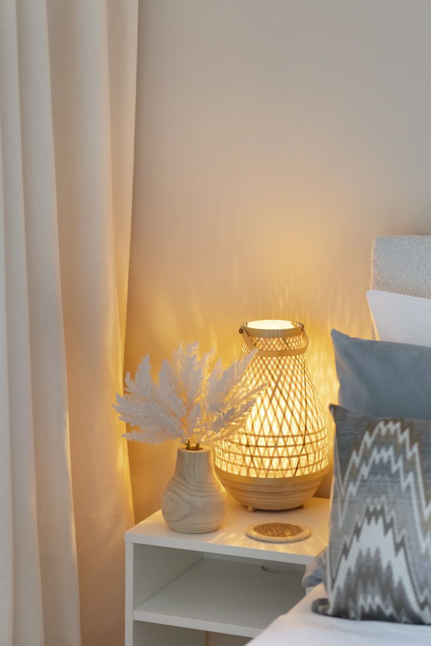 Une table de chevet avec une lampe blanche et des objets décoratifs.