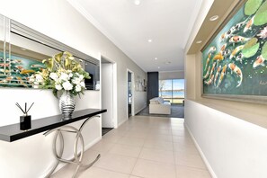 A modern hallway with a black console table, a vase of flowers, and a large koi fish painting on the wall.