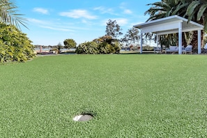 A well-maintained lawn with a gazebo, seating area, and surrounding greenery.