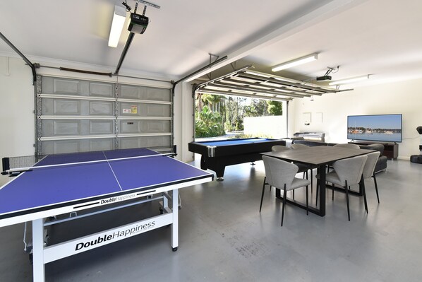 A recreational room with a ping pong table, pool table, and seating area.