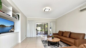 Una sala de estar moderna con un televisor de pantalla plana, un sofá de cuero marrón y una mesa de centro.