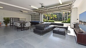 Un espacio interior amplio con mesa de billar, un sofá de cuero negro y una mesa de comedor con sillas.