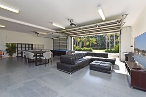 A spacious indoor area with a pool table, a black leather sofa, and a dining table with chairs. - Lake Palm Resort Luxury Waterfront on 3 acres (Dora Creek)