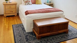 A bedroom with a bed, bedside tables, a ceiling fan, a window, and a rug.