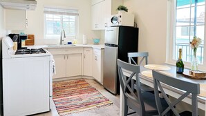 A compact kitchen with a gas stove, refrigerator, and a dining area with a table and chairs.
