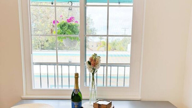 A dining area with a table set for two, a bottle of champagne, and a vase of flowers.