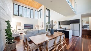A modern open-plan living space with a dining area, kitchen, and large windows.