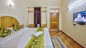 A hotel room with a wooden ceiling, a bed with green and white bedding, a television on the wall, and a wooden door. - Hotel Thakur (Manali)