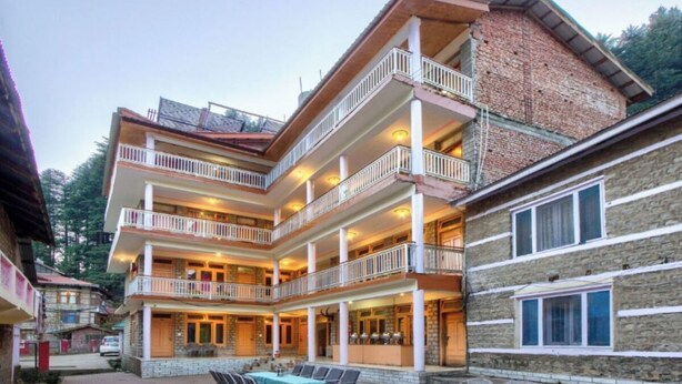 A multi-story hotel with balconies, outdoor seating, and a stone facade. - Hotel Thakur (Manali)