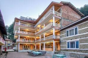 A multi-story hotel with balconies, outdoor seating, and a stone facade. - Hotel Thakur (Manali)