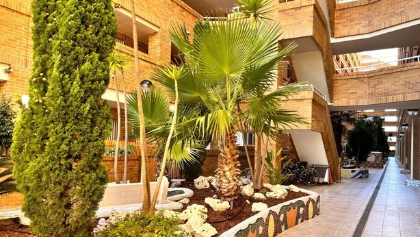 A multi-level atrium with brick walls, indoor plants, and a tiled walkway. - ACV - Torremar-2ª Linea Planta 1 Norte 3H (OROPESA)