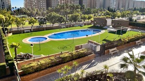 A residential area with a swimming pool, green lawns, and apartment buildings in the background. - ACV - Torremar-2ª Linea Planta 1 Norte 3H (OROPESA)