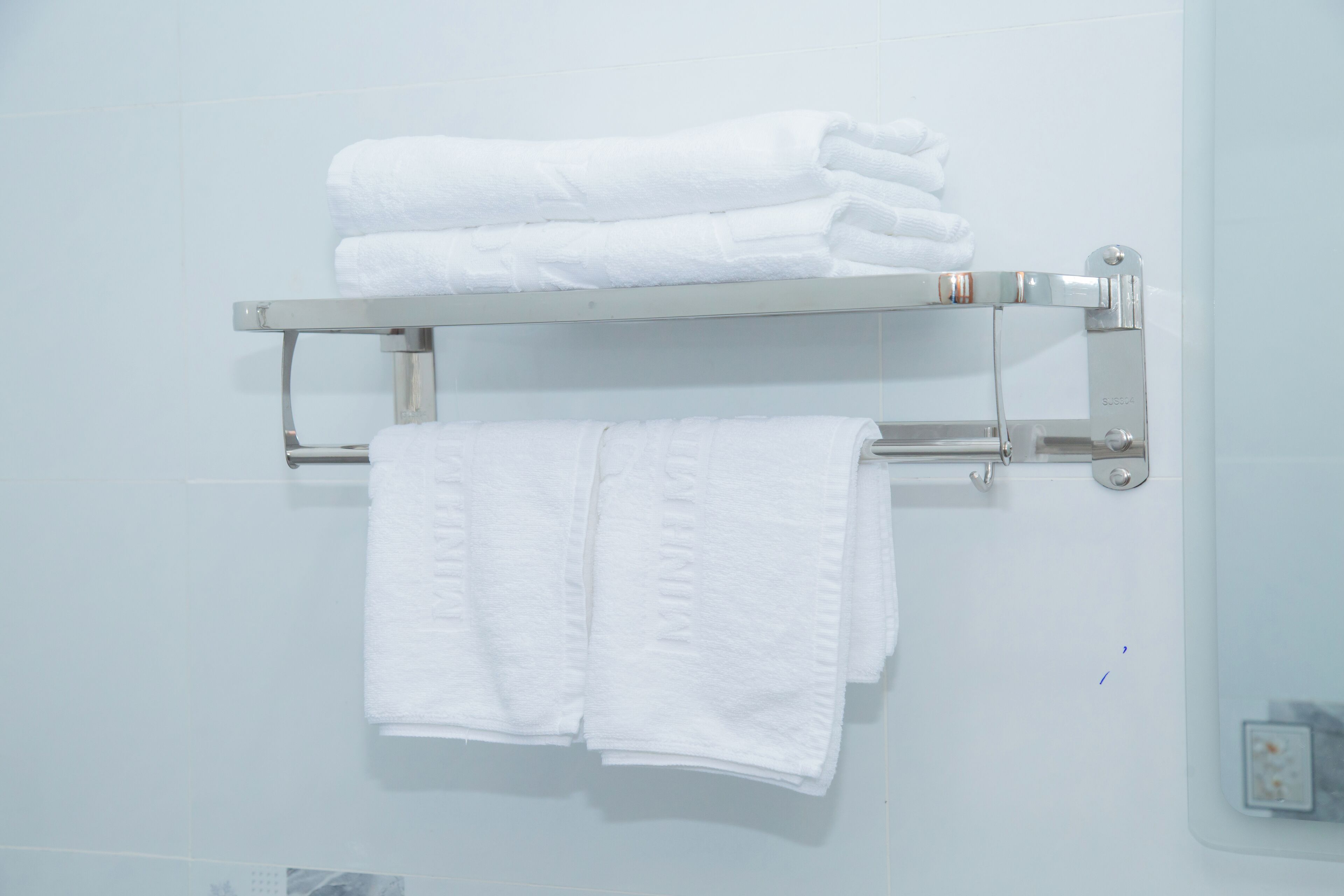 A bathroom with a white towel rack holding folded towels.