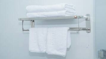 A bathroom with a white towel rack holding folded towels.