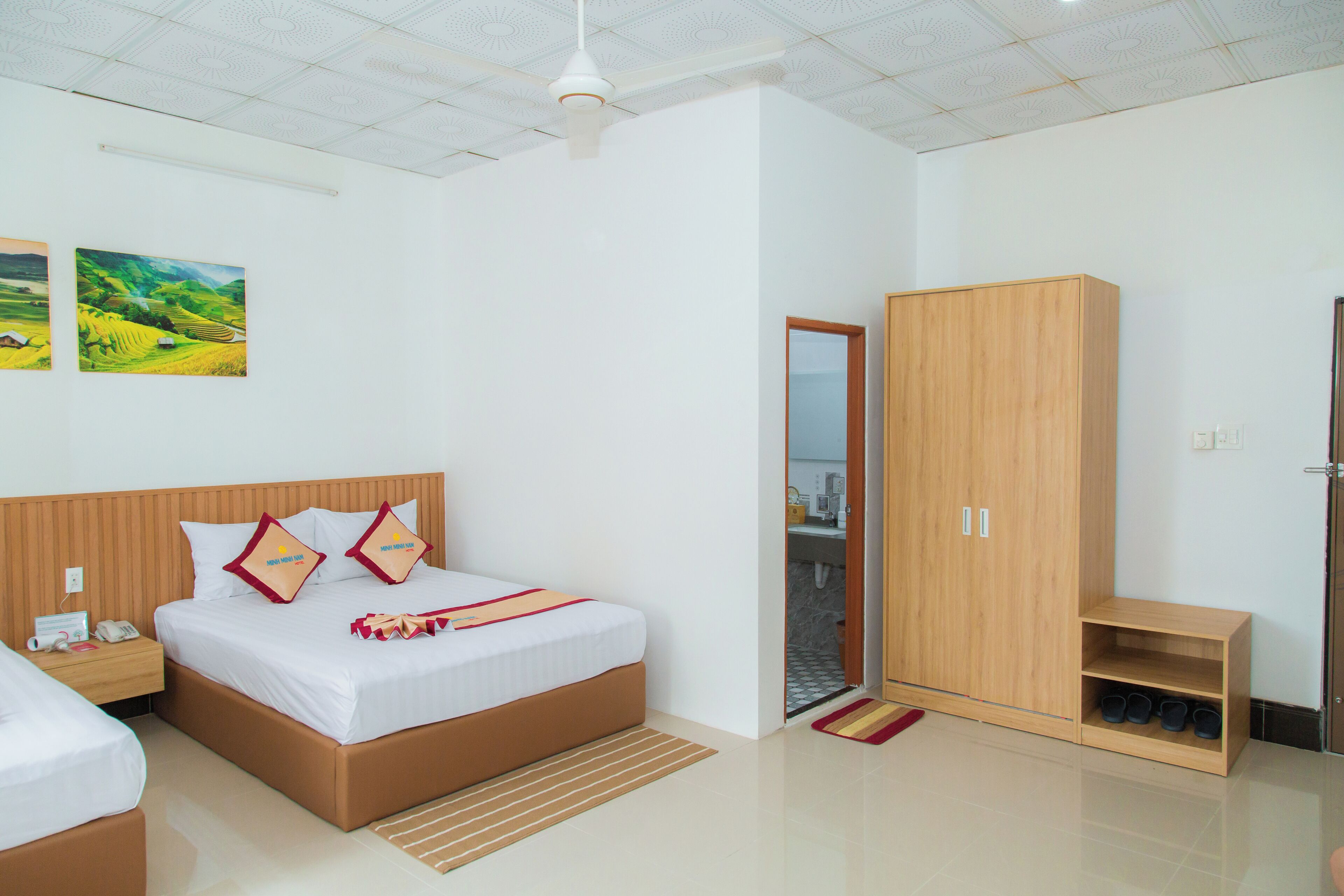 Una camera d'albergo moderna con un letto grande, un armadio in legno e una piccola area salotto.
