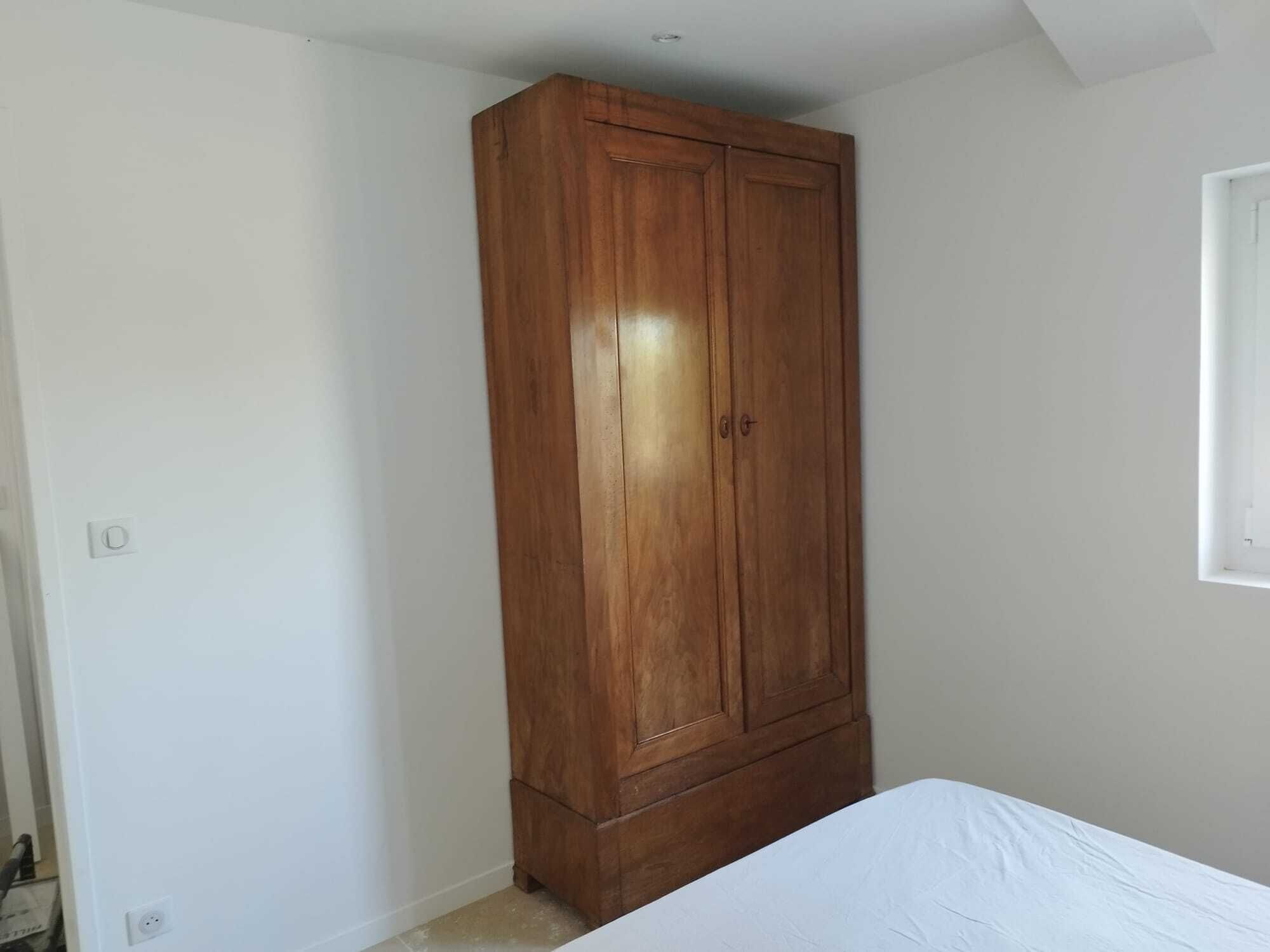 Un dormitorio con un armario de madera, una cama y una ventana.