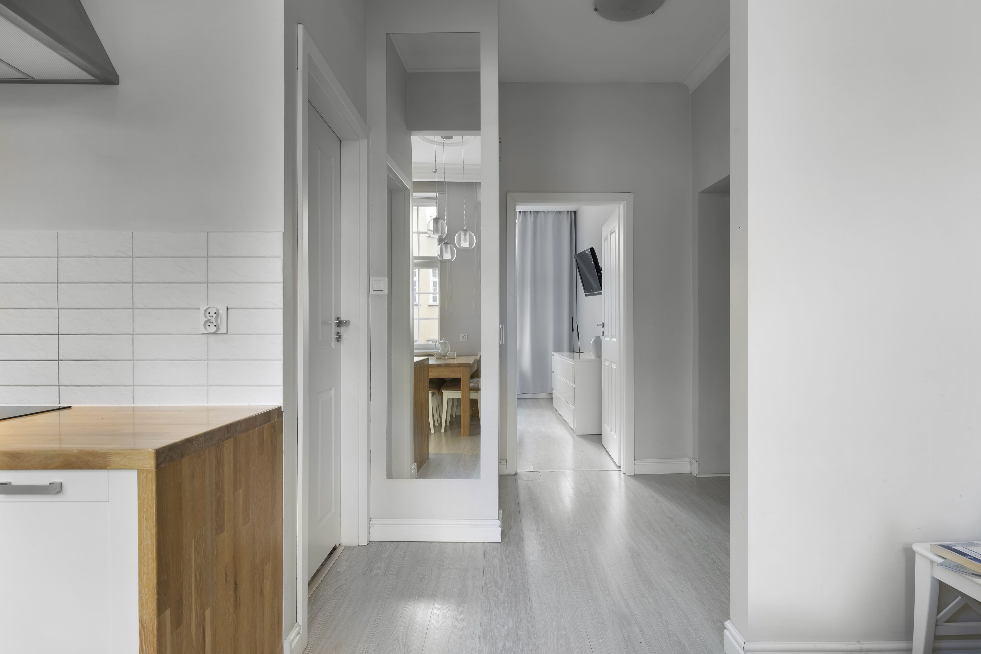 A modern kitchen with white cabinetry and a wooden countertop.
