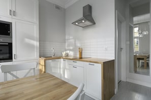 A modern kitchen with white cabinets, a wooden countertop, and a built-in oven. - Elite Apartments Mariacka Premium  (Gdansk)