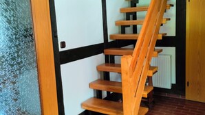 A wooden staircase with black accents, a glass door, and a brick floor.