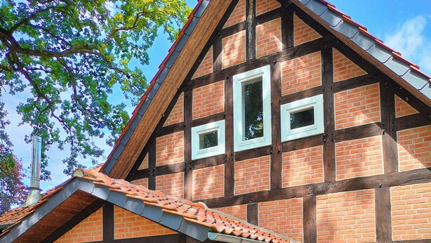 A traditional half-timbered house with a covered porch, a bench, and a potted plant.