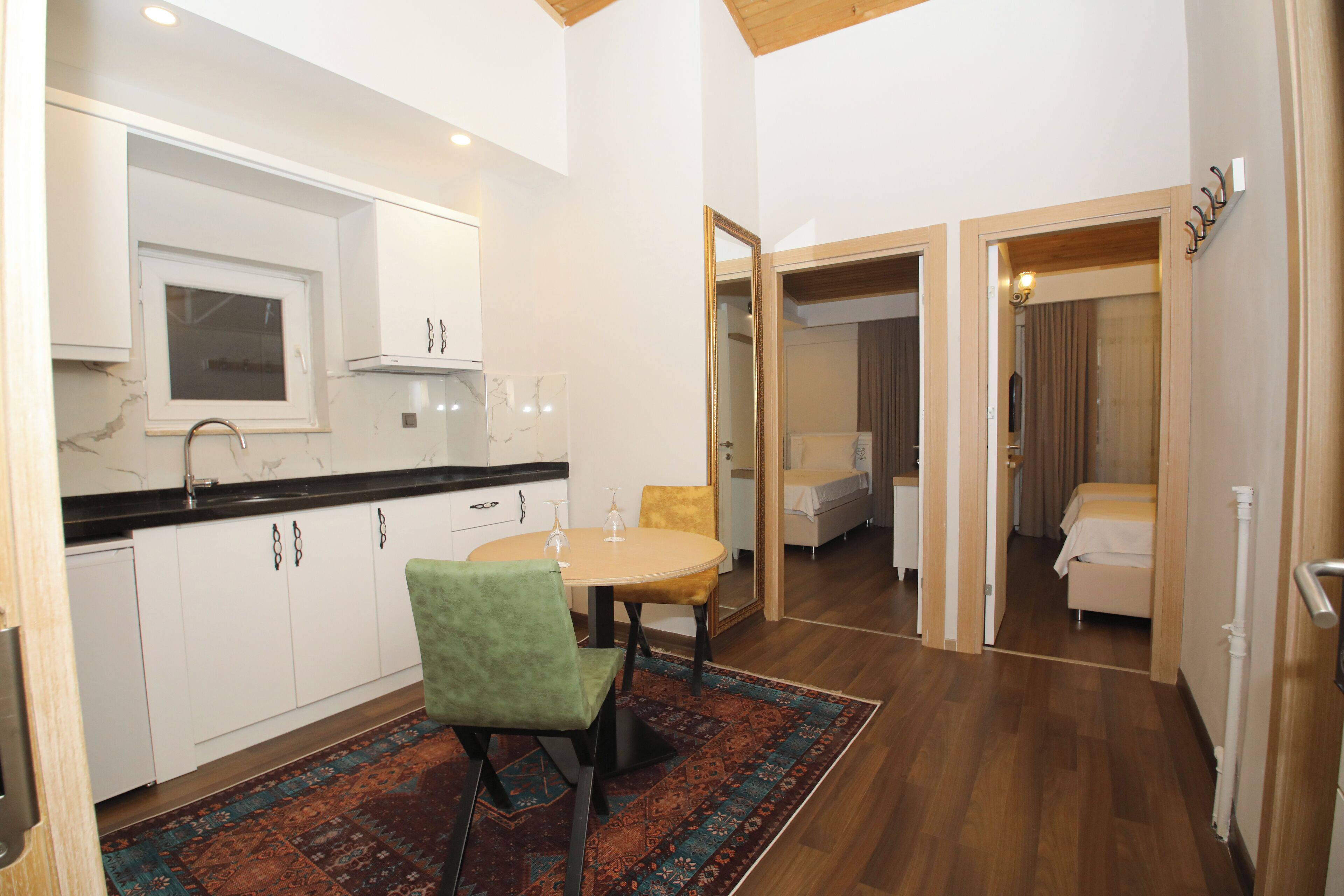 A modern kitchen with white cabinets, a marble countertop, and a dining area with a round table and chairs.