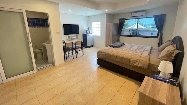 A modern hotel room with a bed, desk, chair, and a TV. - The Sports Lounge (Pattaya)