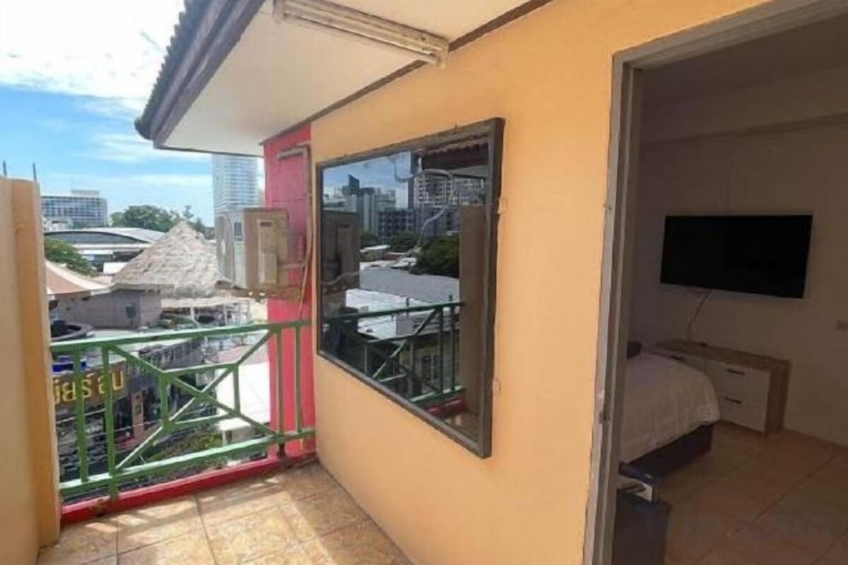 Un balcon avec vue sur les immeubles, un lit avec un téléviseur et une fenêtre.
