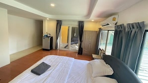 A hotel room with a bed, a desk with a computer, a wardrobe, and a sliding glass door leading to a balcony. - The Sports Lounge (Pattaya)