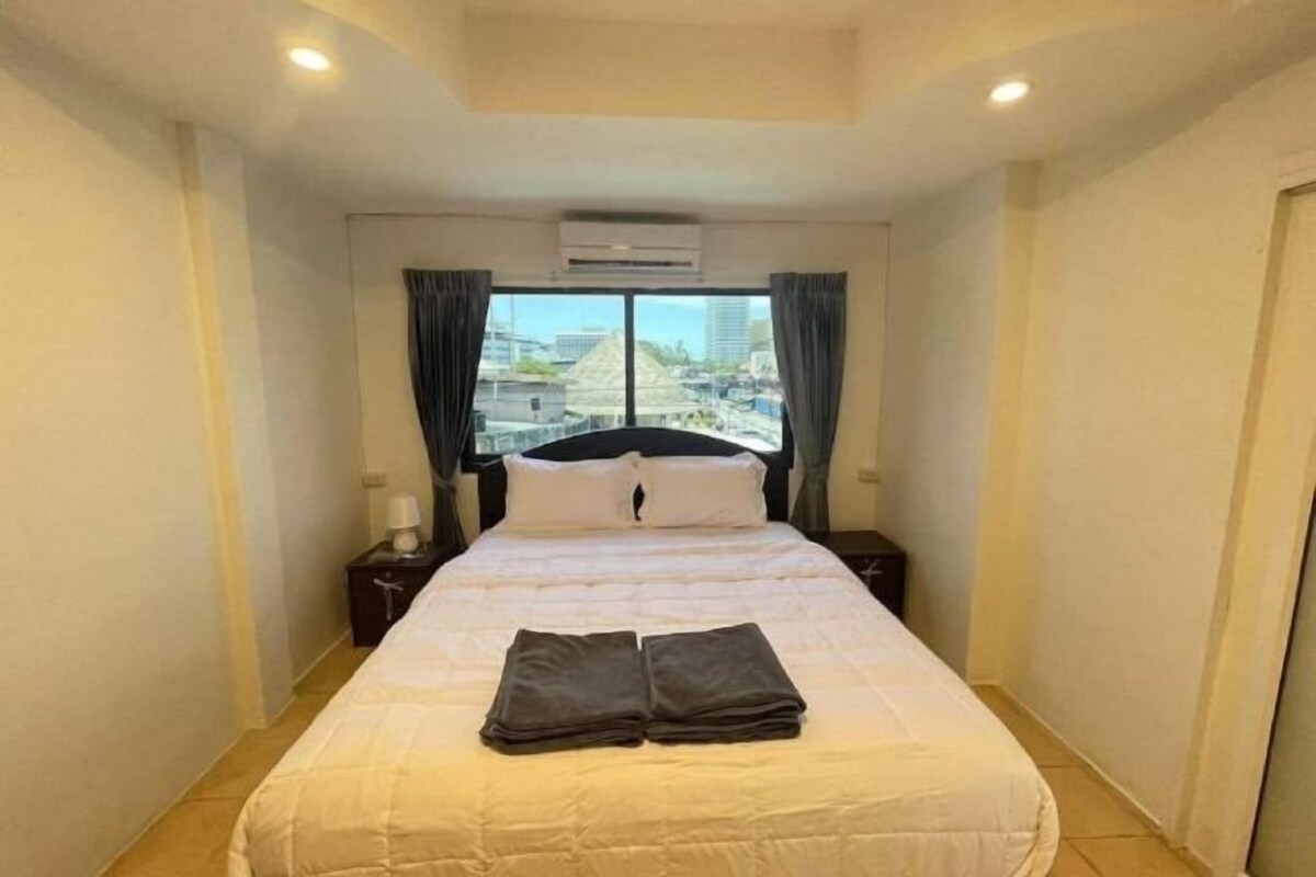 Quarto de hotel com uma cama, mesa de cabeceira, ar condicionado e uma janela com cortinas.