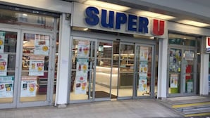 A Super U store with glass doors and multiple promotional posters. - Appartement Paris (Paris)