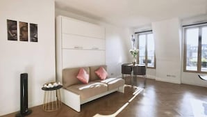 A modern living room with a sofa, a small side table, and a tall floor lamp. - Appartement Paris (Paris)