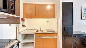 A compact kitchen with wooden cabinets, a stainless steel sink, and a stove.