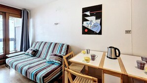 A cozy room with a striped sofa, a wooden table, and a kettle.