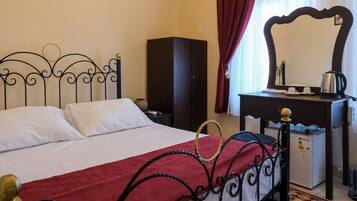 Una habitación de hotel con cama, cómoda, espejo y un mueble pequeño.