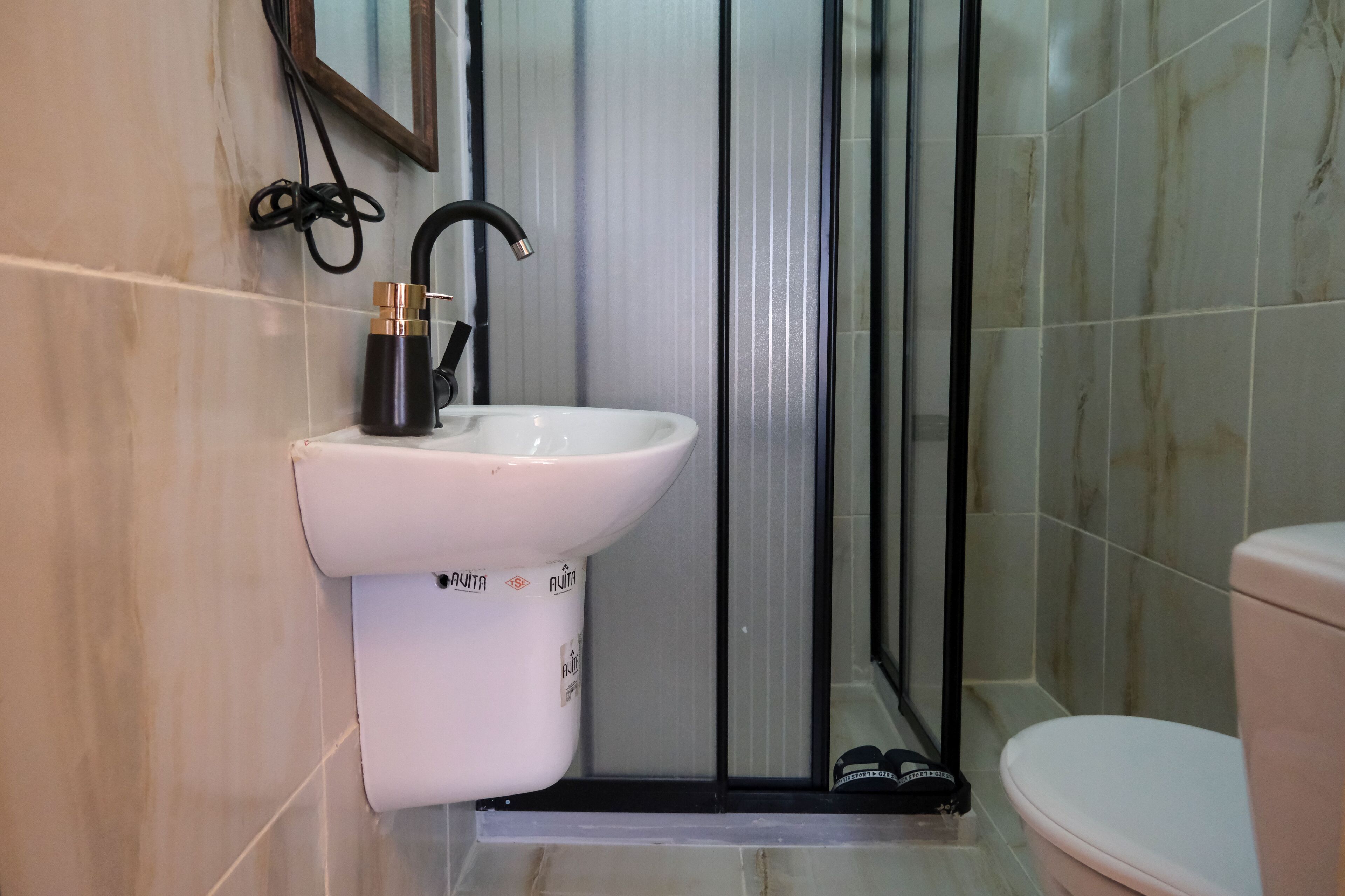 A bathroom with a white sink, black faucet, and a toilet.