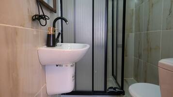 A bathroom with a white sink, black faucet, and a toilet.