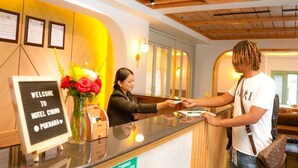 A hotel reception desk with a welcome sign, a vase of flowers, and a guest interacting with a staff member. - Hotel Chino Pokhara Pvt. Ltd. (Pokhara)