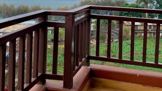 A balcony with a view of a lake and mountains. - Hotel Chino Pokhara Pvt. Ltd. (Pokhara)
