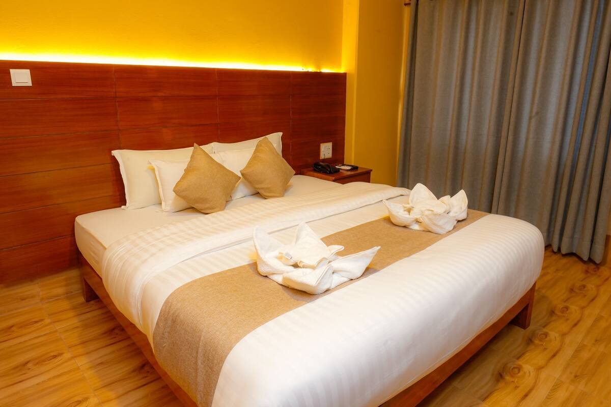 Une chambre d’hôtel avec un grand lit, une tête de lit en bois et une table de chevet avec un téléphone et une lampe.