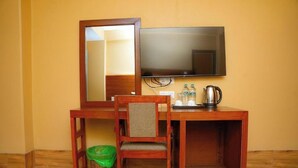 A wooden desk with a television, a chair, a trash bin, and a kettle. - Hotel Chino Pokhara Pvt. Ltd. (Pokhara)