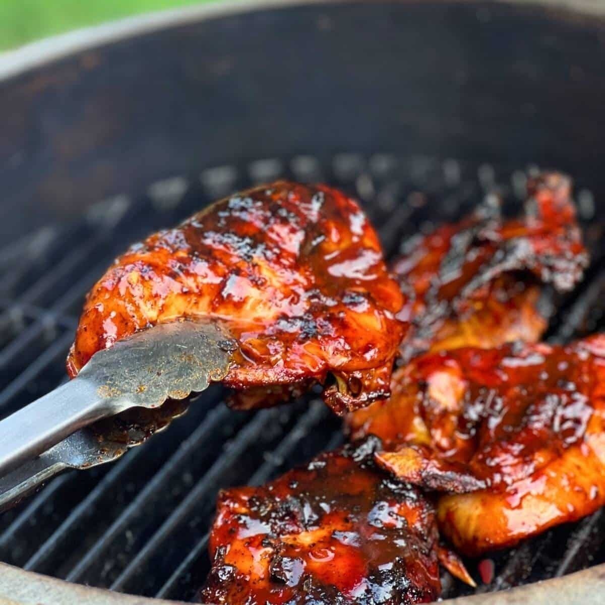 Grilled meat with a glossy sauce on a grill.