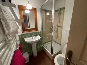 Une salle de bain équipée d’un lavabo, d’un miroir, d’une douche, de toilettes et de serviettes.