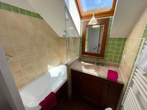 A bathroom with a bathtub, a sink, a mirror, and a window.