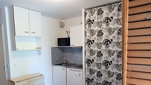 Una cocina compacta con armarios blancos, un microondas y un lavamanos.