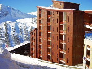 A multi-story building with balconies, surrounded by snow-covered mountains. - Studio for 3 in the center of Arc 2000 with balcony (Les Arcs 2000)